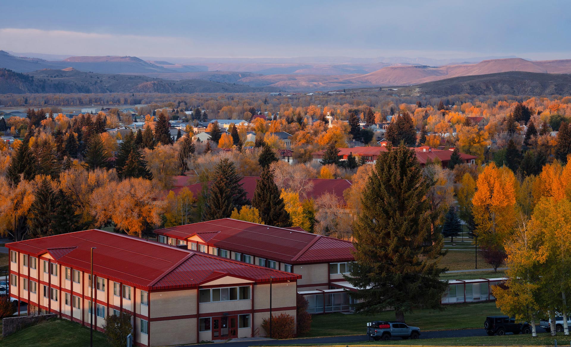 A photo of campus in the fall with Crystal Hall in the foreground, just before sunrise.