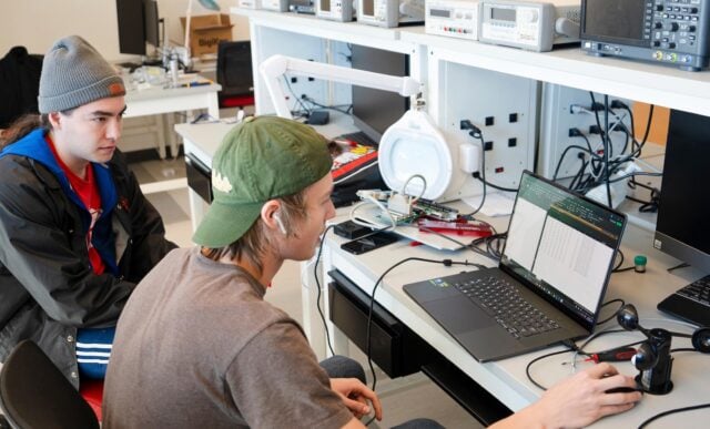 Two engineering students look at the screen of a laptop while assembling a sensory suite for the Rocky Mountain Biological Lab.