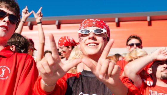 A fan holds up a W in the student section of a football game.