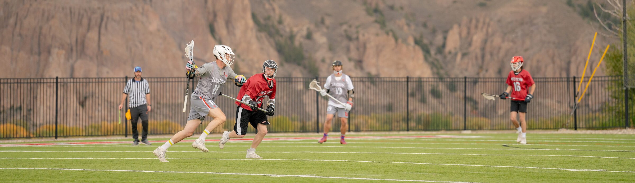 Club Sports lacrosse athletes play on Katy O. Rady Field with the Palisades rock formation seen in the background.