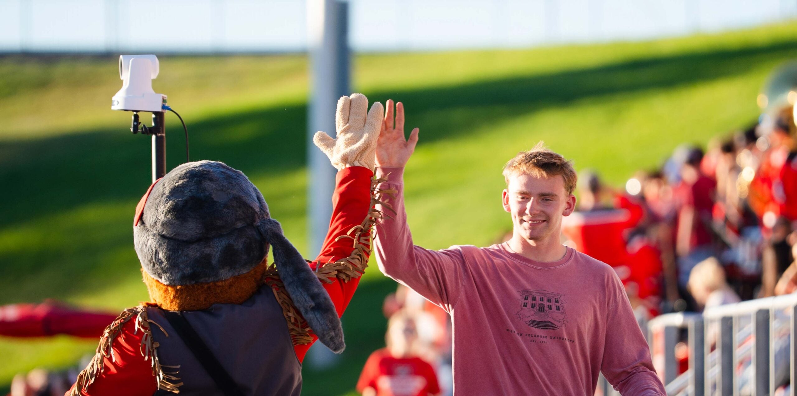 Mad Jack high fives a student walking out of the football stadium.