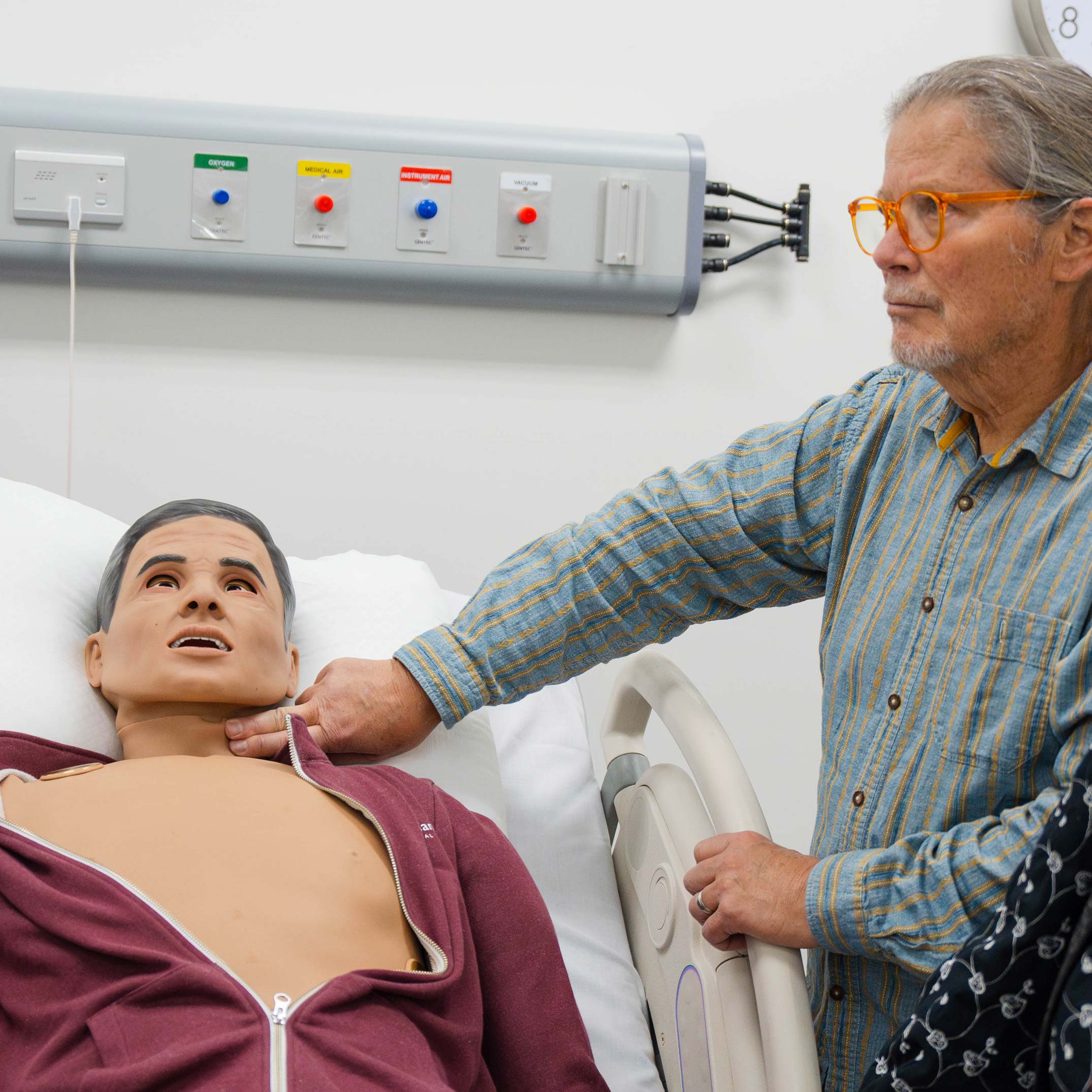 A man feels the pulse of a medical mannikin.