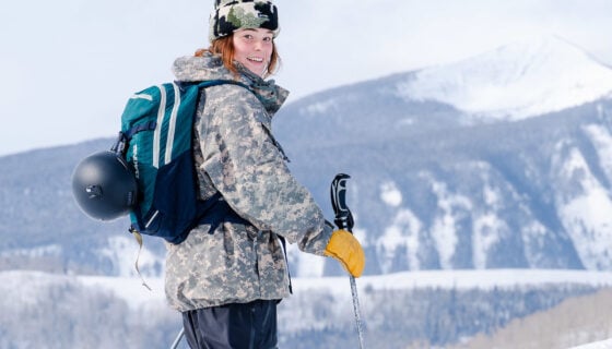 Clara Lantz smiles as she skins up Snodgrass Mountain. Frosty mountains are seen behind her.