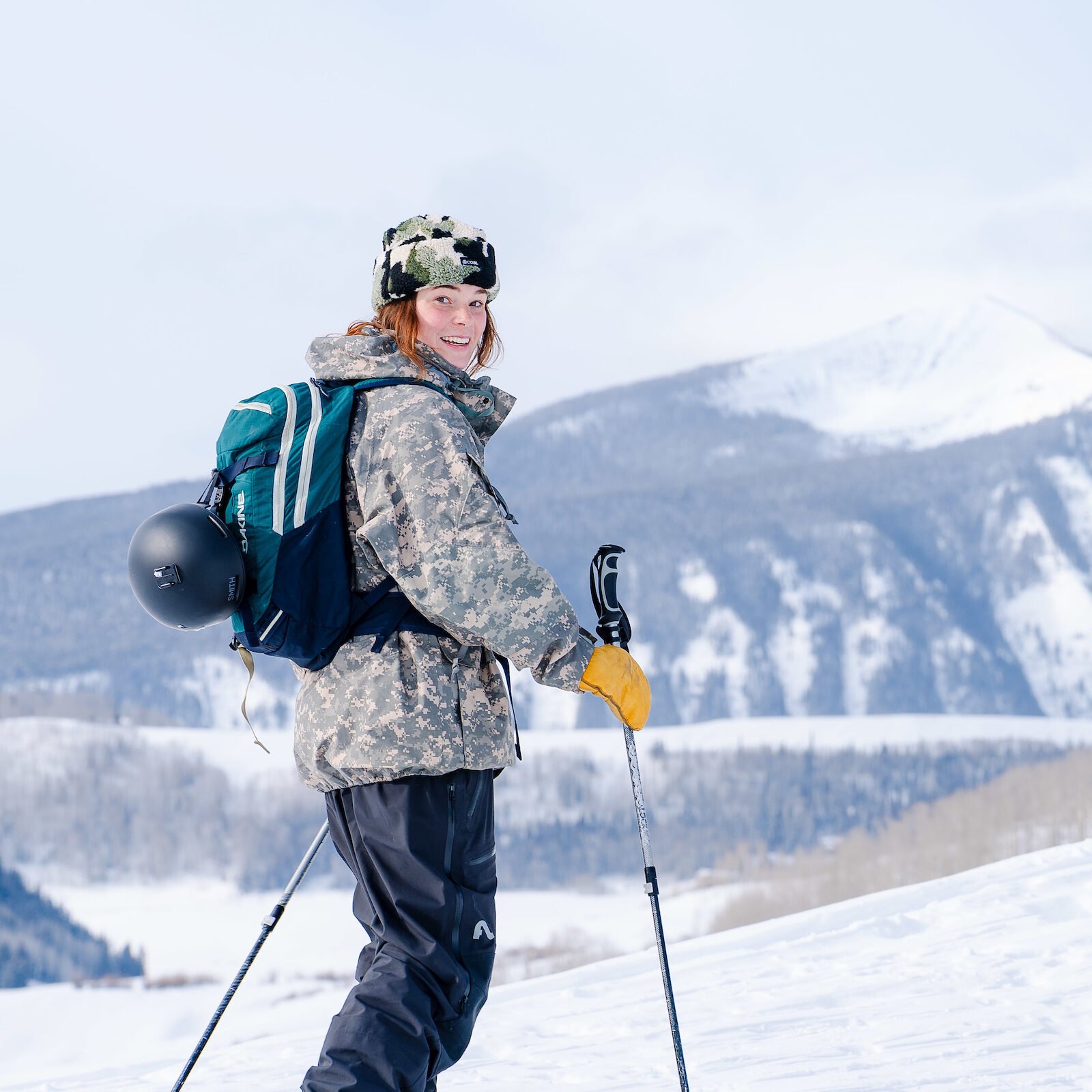 Clara Lantz smiles as she skins up Snodgrass Mountain. Frosty mountains are seen behind her.