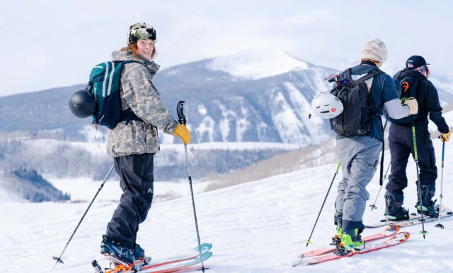 Clara Lantz smiles as she skins up Snodgrass Mountain. Frosty mountains are seen behind her.