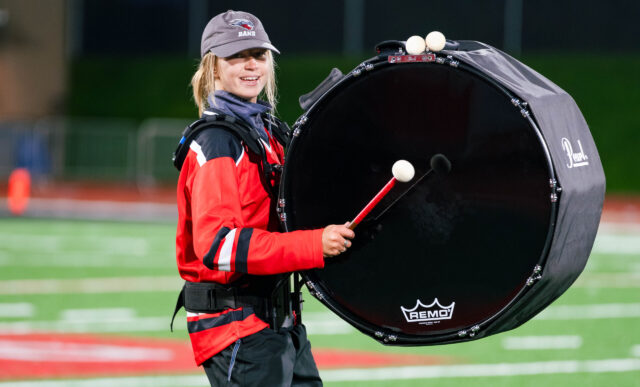 A member of the Western drumline plays the bass drum on the field at half-time.