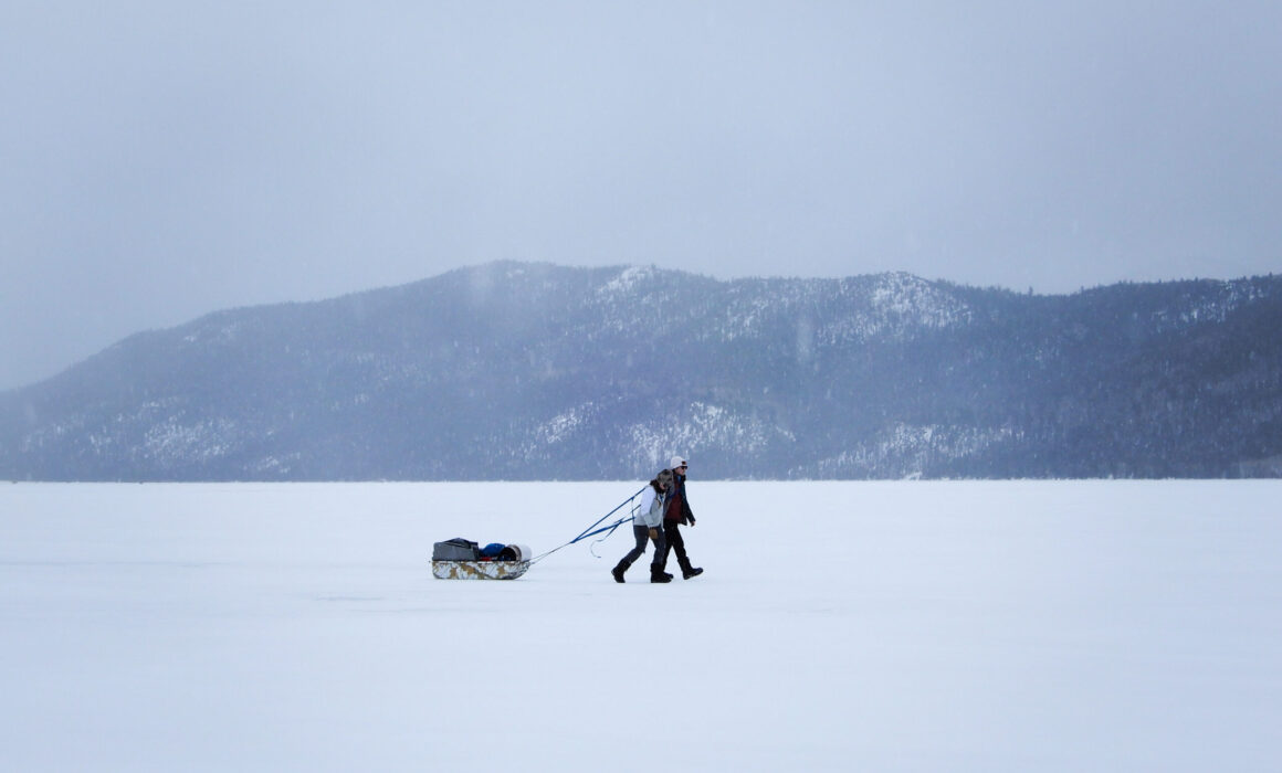 Two students drag a sled as they walk across a frozen lake in Utah.