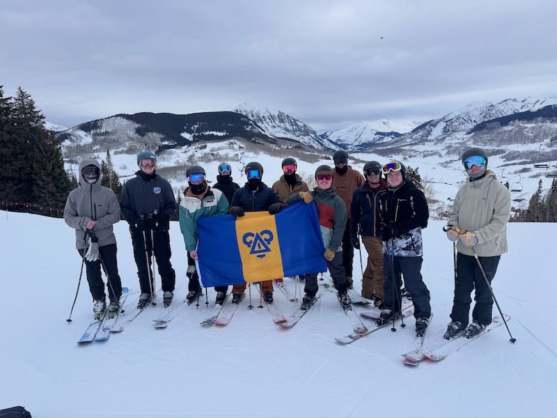 Delta Upsilon Fraternity poses for a group shot on the ski slopes.