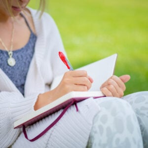 A close up shot of a student writing in her journal on Taylor Lawn