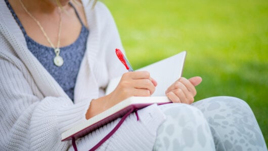 A close up shot of a student writing in her journal on Taylor Lawn