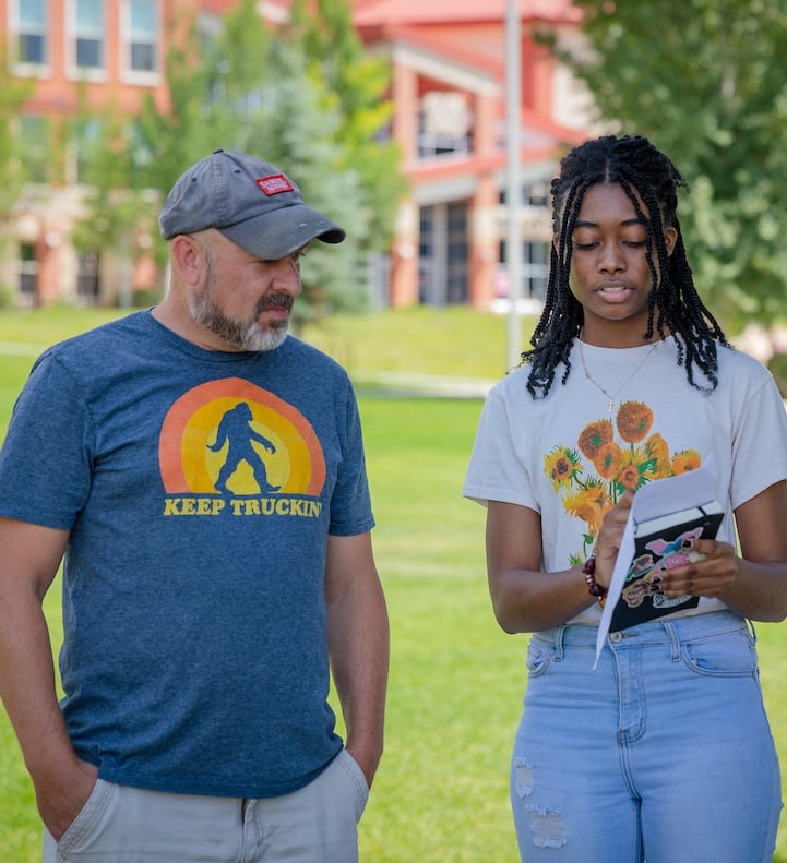 A screenwriting student checks his script with the director of the short film they are making in class on the lawn outside of the Welcome Center