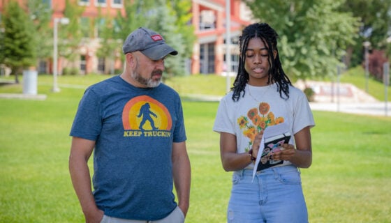 A screenwriting student checks his script with the director of the short film they are making in class on the lawn outside of the Welcome Center
