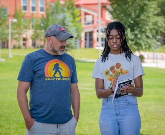 A screenwriting student checks his script with the director of the short film they are making in class on the lawn outside of the Welcome Center