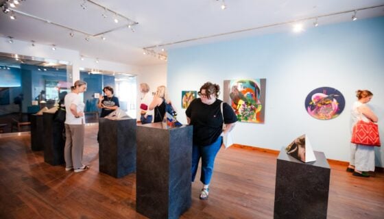 A student observes artwork on pedestals inside the Center for the Arts art gallery.