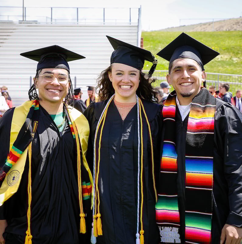 Three graduates pose for a photo after the 2021 commencement ceremony.