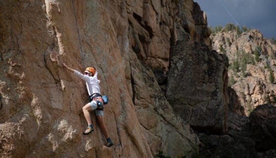 An incoming student climbs up a route on Left Hand in Taylor Canyon during Wilderness Based Orientation.
