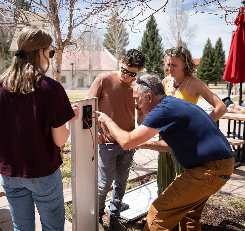 Rich Stromberg demonstrates how to attach a USB port to a solar panel for some students.