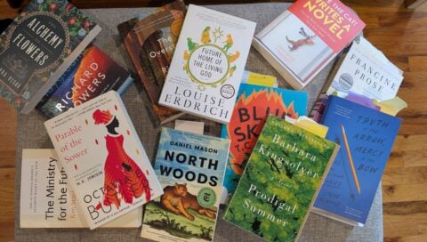 An assorted pile of books on a coffee table.