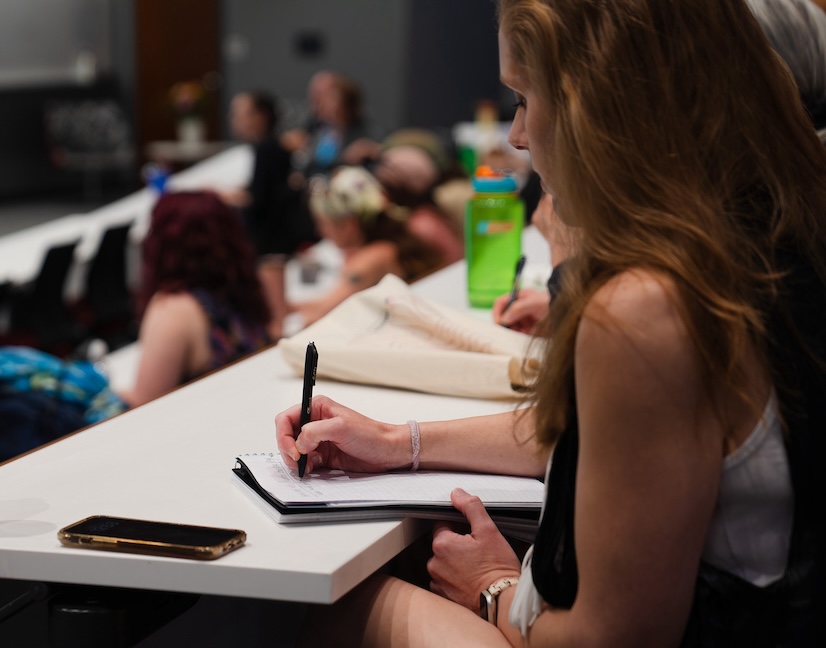 A GPCW student takes notes at a craft talk during the 2025 summer residency.