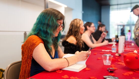 Publishing student signs books for attendees at the GPCW publishing event.