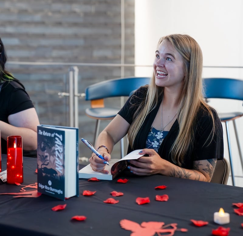 A publishing student signs copies of her book for attendees of the GPCW publishing event,