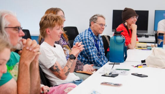 Poetry students smile while listening during a discussion in class for the GPCW summer residency.