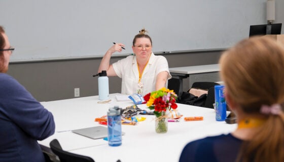 A professor sits at a table with her screenwriting students and engages in discussion during a class for the GPCW residency.