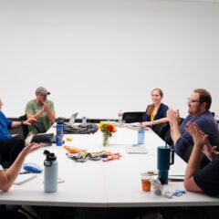 Screenwriting students sit around a table and clap for their peer after she shared some of her writing during class for the GPCW summer residency.