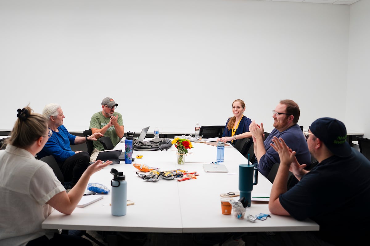Screenwriting students sit around a table and clap for their peer after she shared some of her writing during class for the GPCW summer residency.