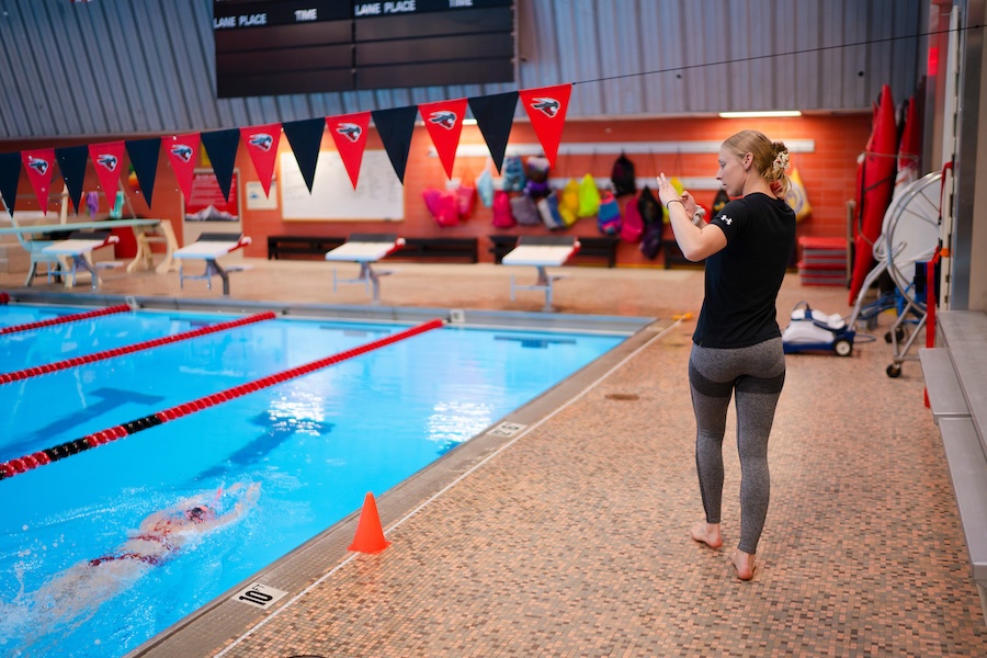 Graduate student, Emily Jauch, with the HAEP program walks the length of the pool as she films a swimmer completing a lap.