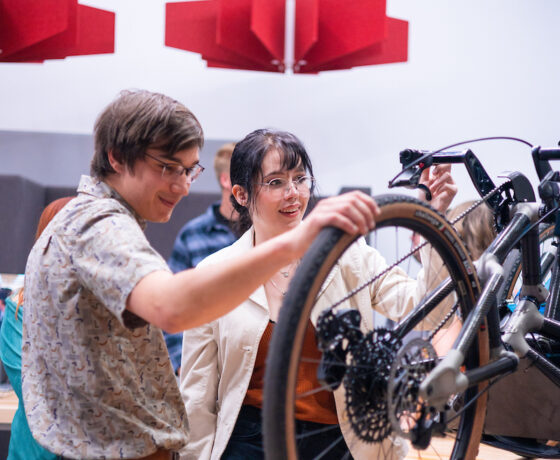 Two students observe the adaptive bike during Industry Night