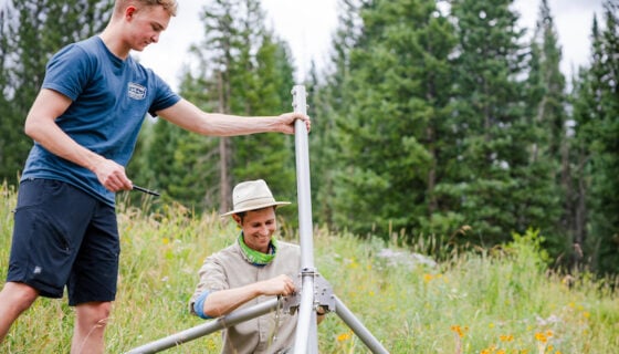 An engineering student helps a RMBL employee build a weather station in Gothic, Colorado.