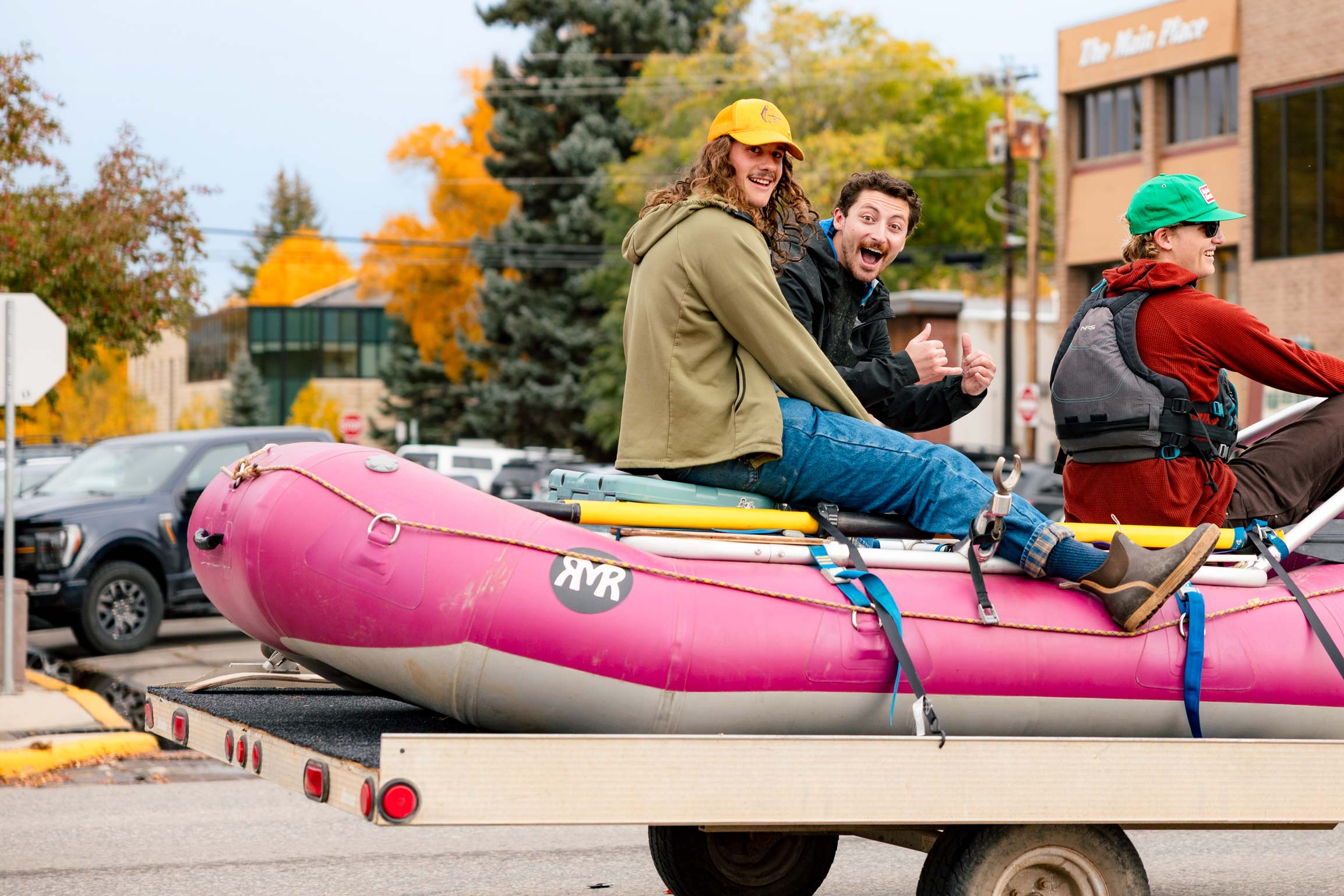 Three students sit on a raft on a trailer during the Homecoming parade on Gunnison's Main Street.