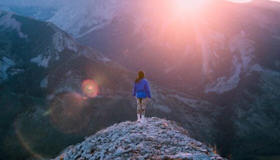 A girl stands on a mountain ridge at sunrise