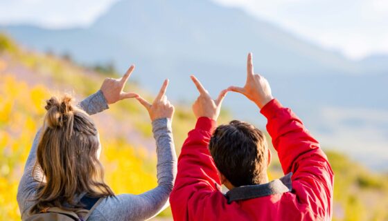 Two students hold the W above their heads in front of Teocalli Mountain at sunrise.