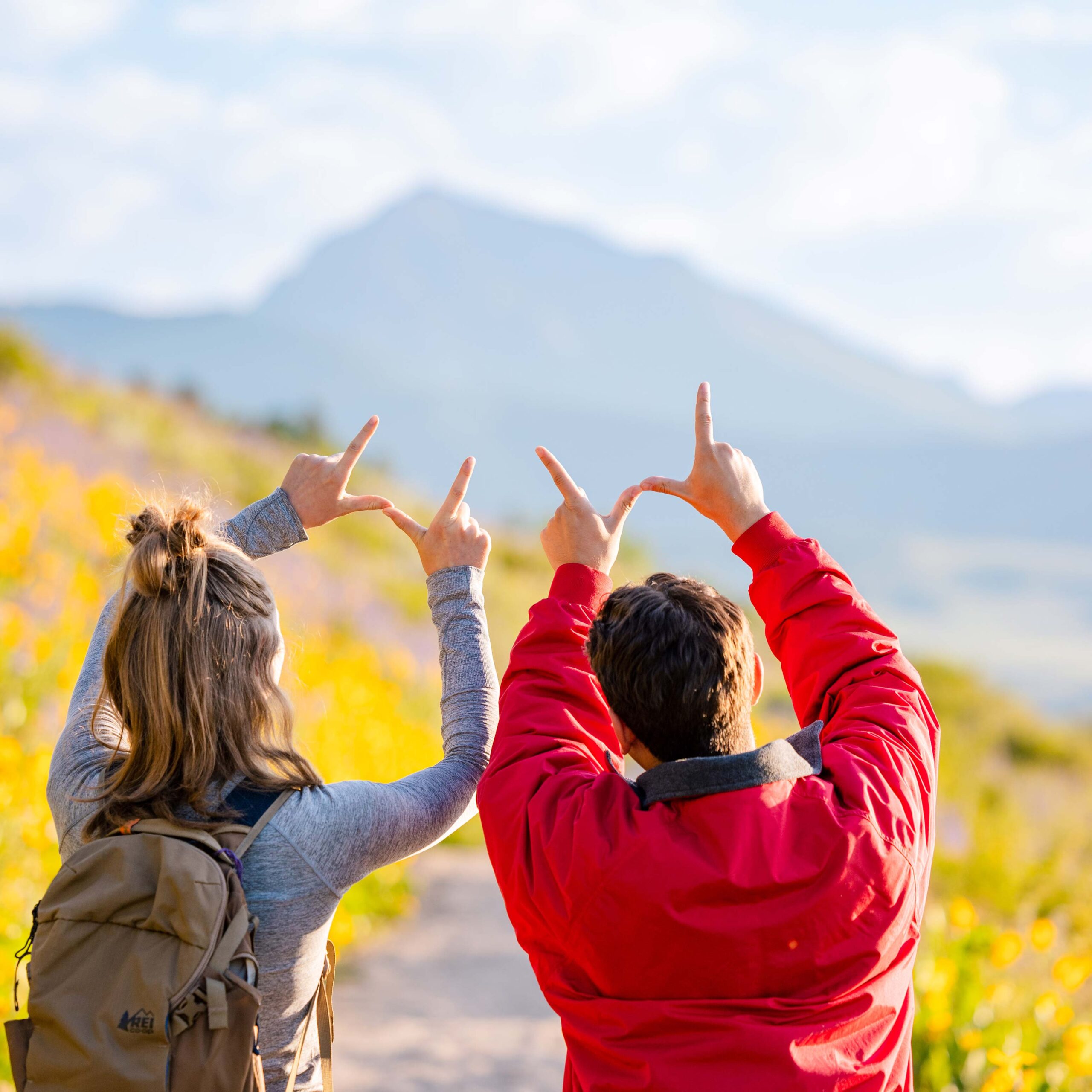 Two students hold the W above their heads in front of Teocalli Mountain at sunrise.