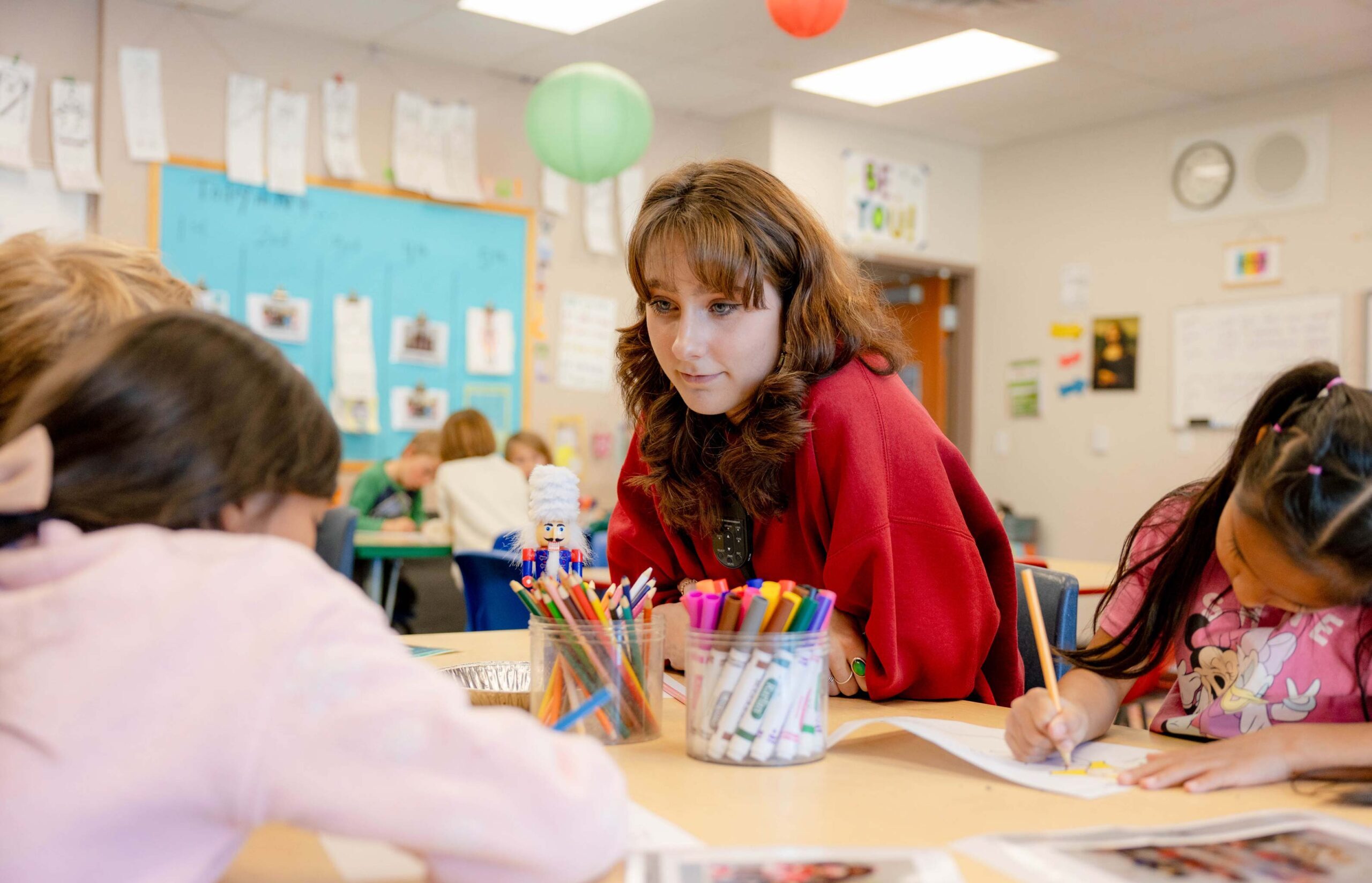 A student teacher sits at a table with her students.