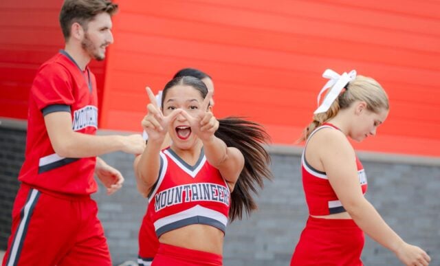 A cheerleader holds up the W while entering the Mountaineer Bowl.