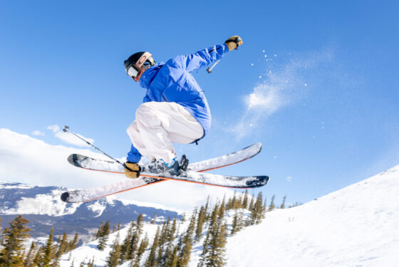 A skier catches air on a blue sky day.