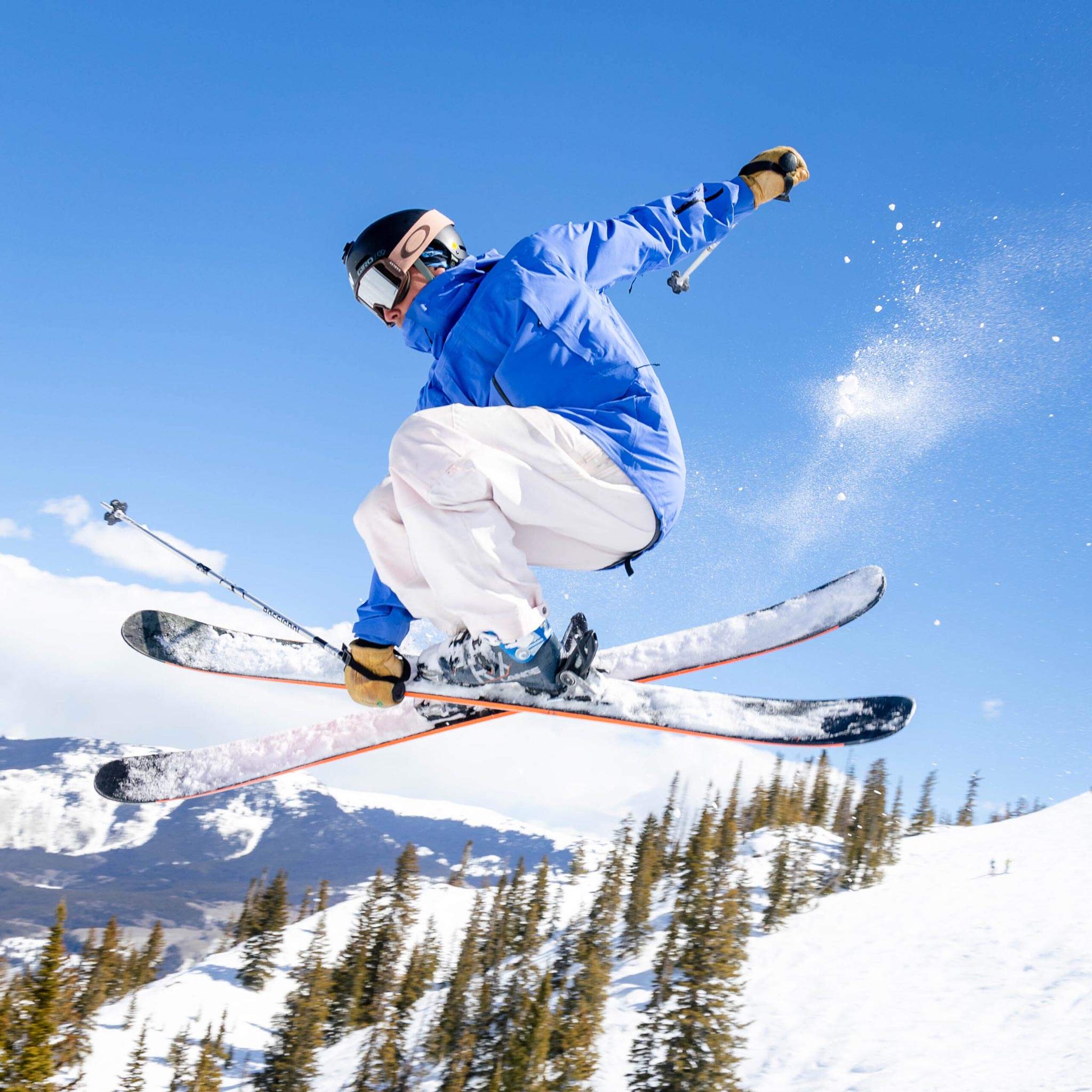 A skier catches air on a blue sky day.