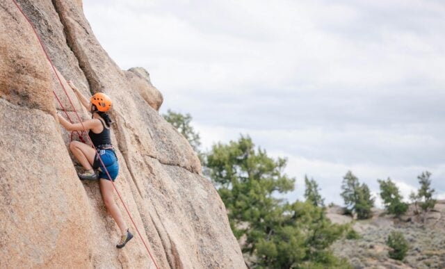 A first-year student rock climbs up Beginner's Slab at Hartman Rocks with Wilderness Pursuits.