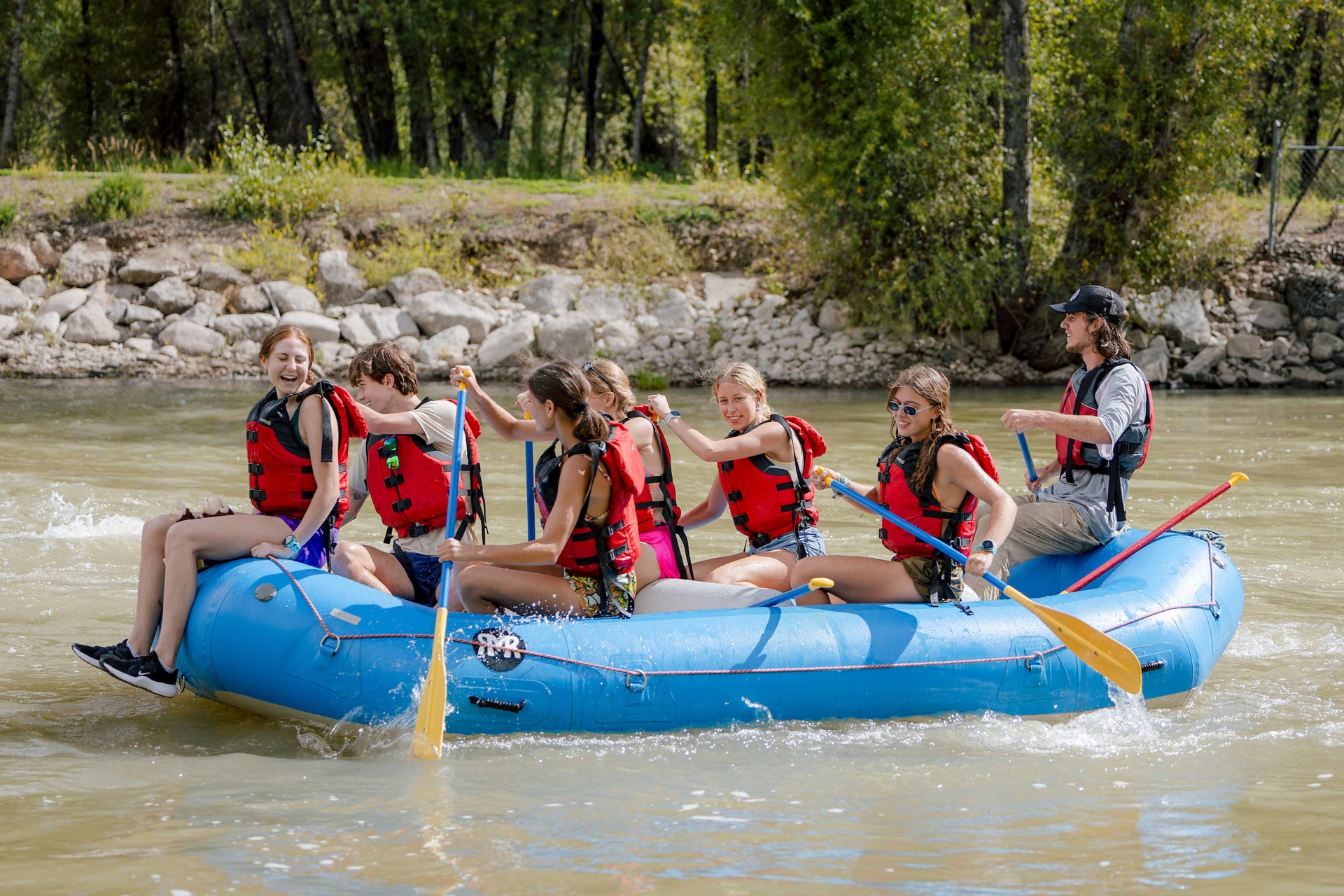 Students float through the rapids at the Gunnison Whitewater Park on a raft with a WP instructor.