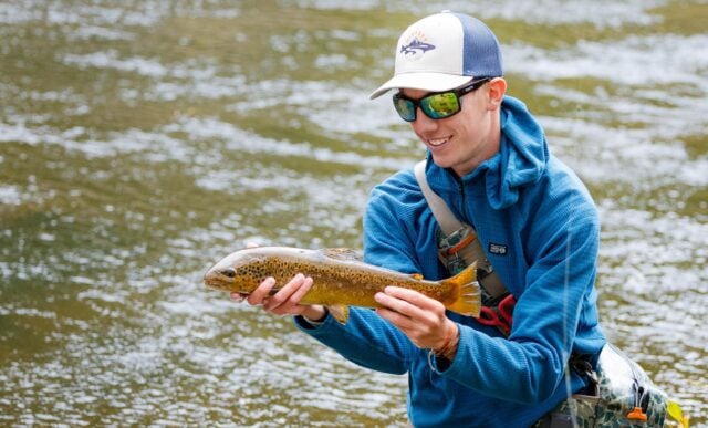 A student displays the beautiful trout he caught during a biology lab.
