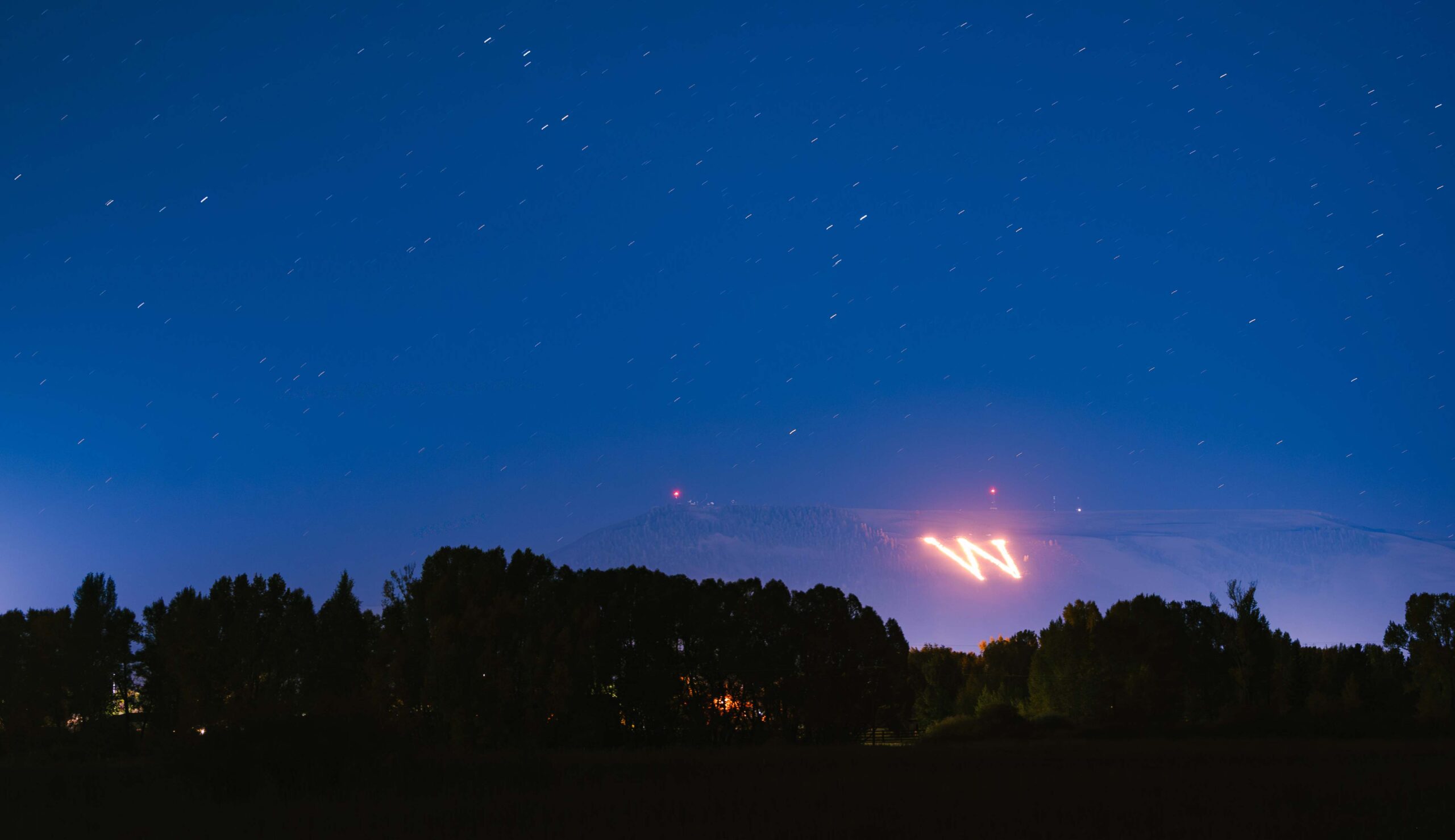 Seen from Van Tuyl Ranch, the collegiate "W" on Tenderfoot Mountain is lit on fire during the first night of Homecoming weekend.