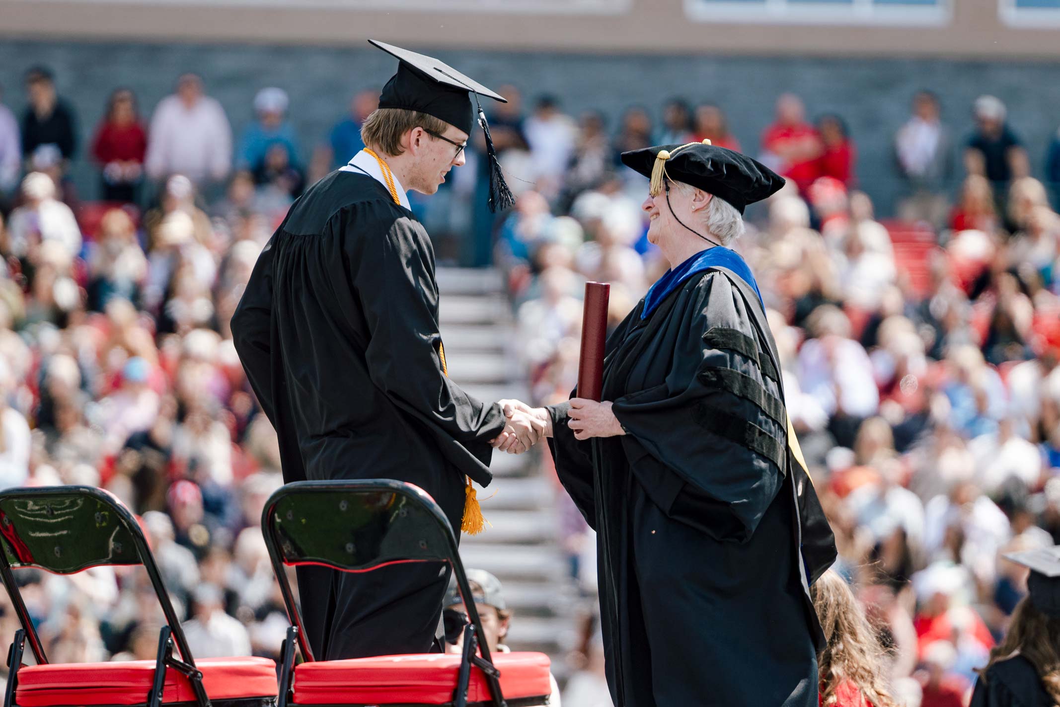 A graduate receives his diploma from Jess Young.