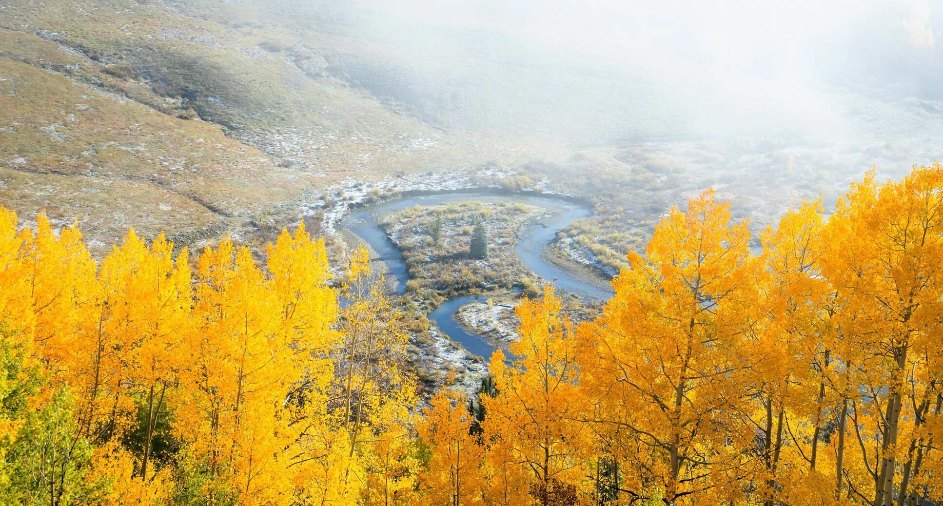 A river bend with fall trees in the foreground.