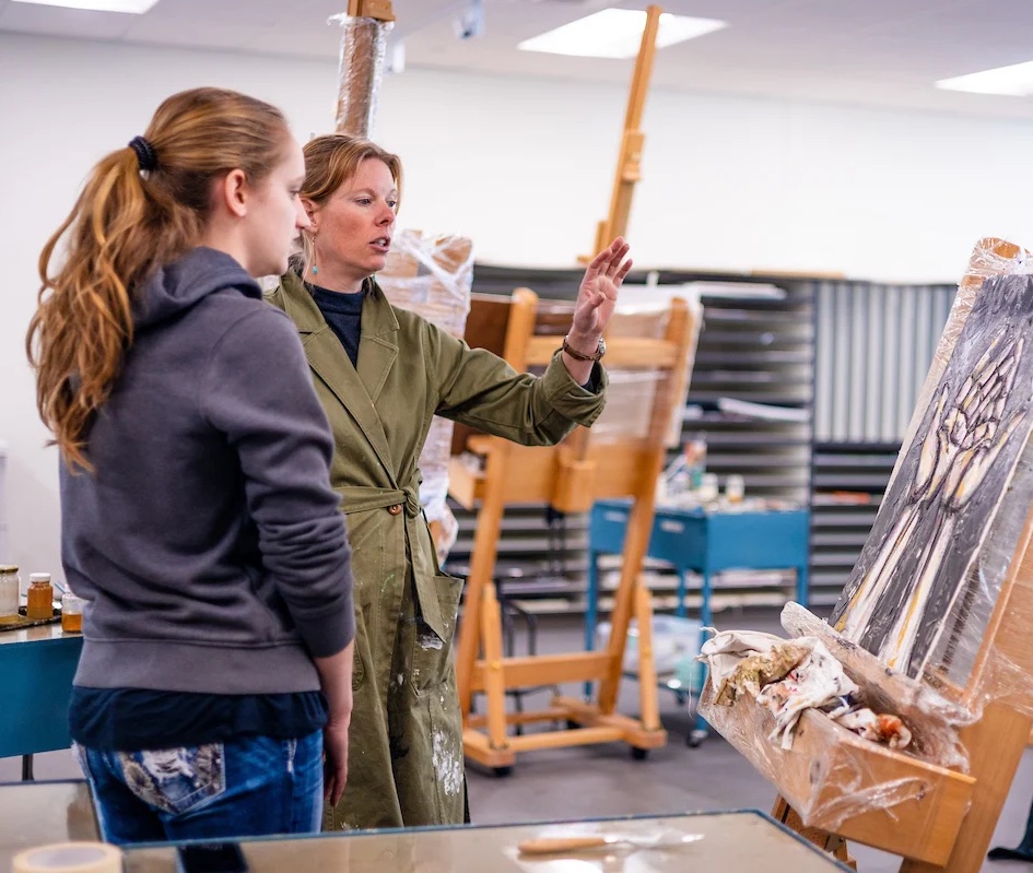A professor critiques a student's artwork.