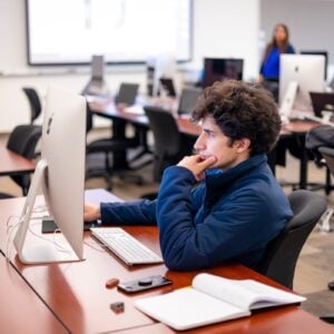 A student is seated at an imac and works on his project in typography class