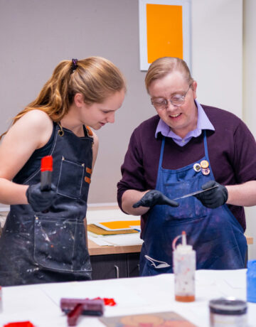 Chase Hutchison assists a student during printmaking class.