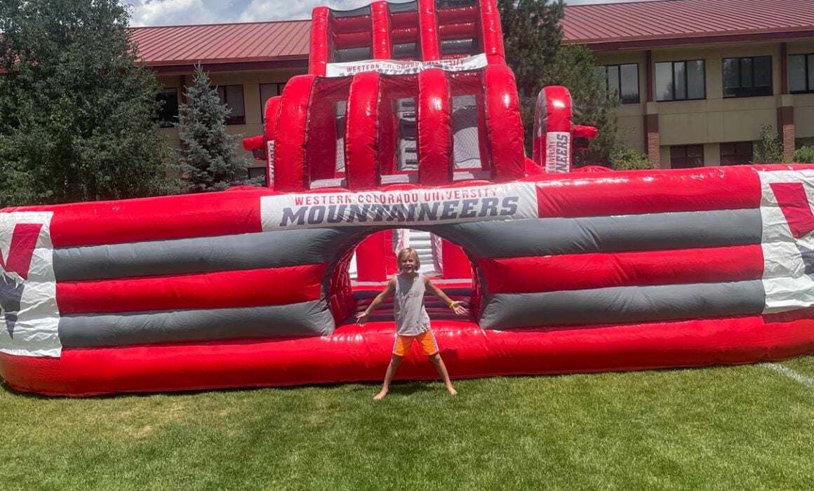 Kid stands in front of a Western branded bouncy house.